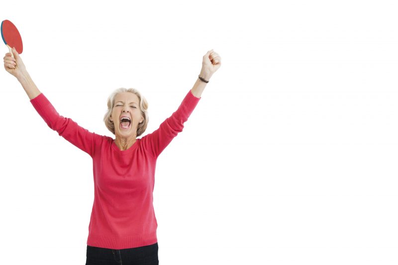 Happy senior female table tennis player with arms raised celebrating victory